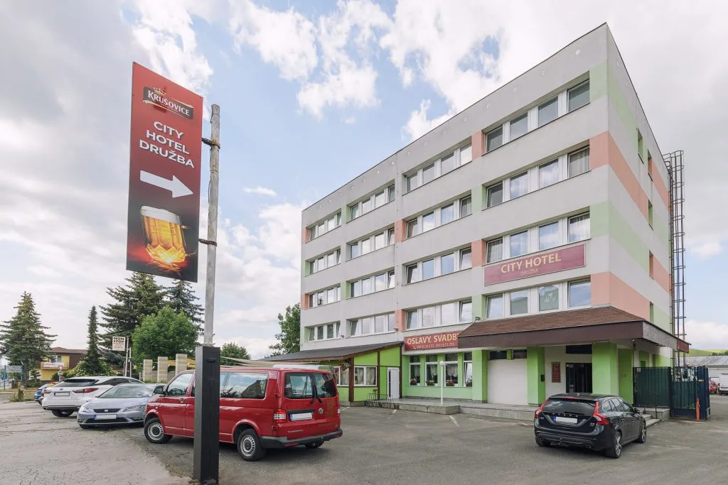 Exterior of City Hotel Družba – a four-storey building with the City Hotel Družba sign above the entrance